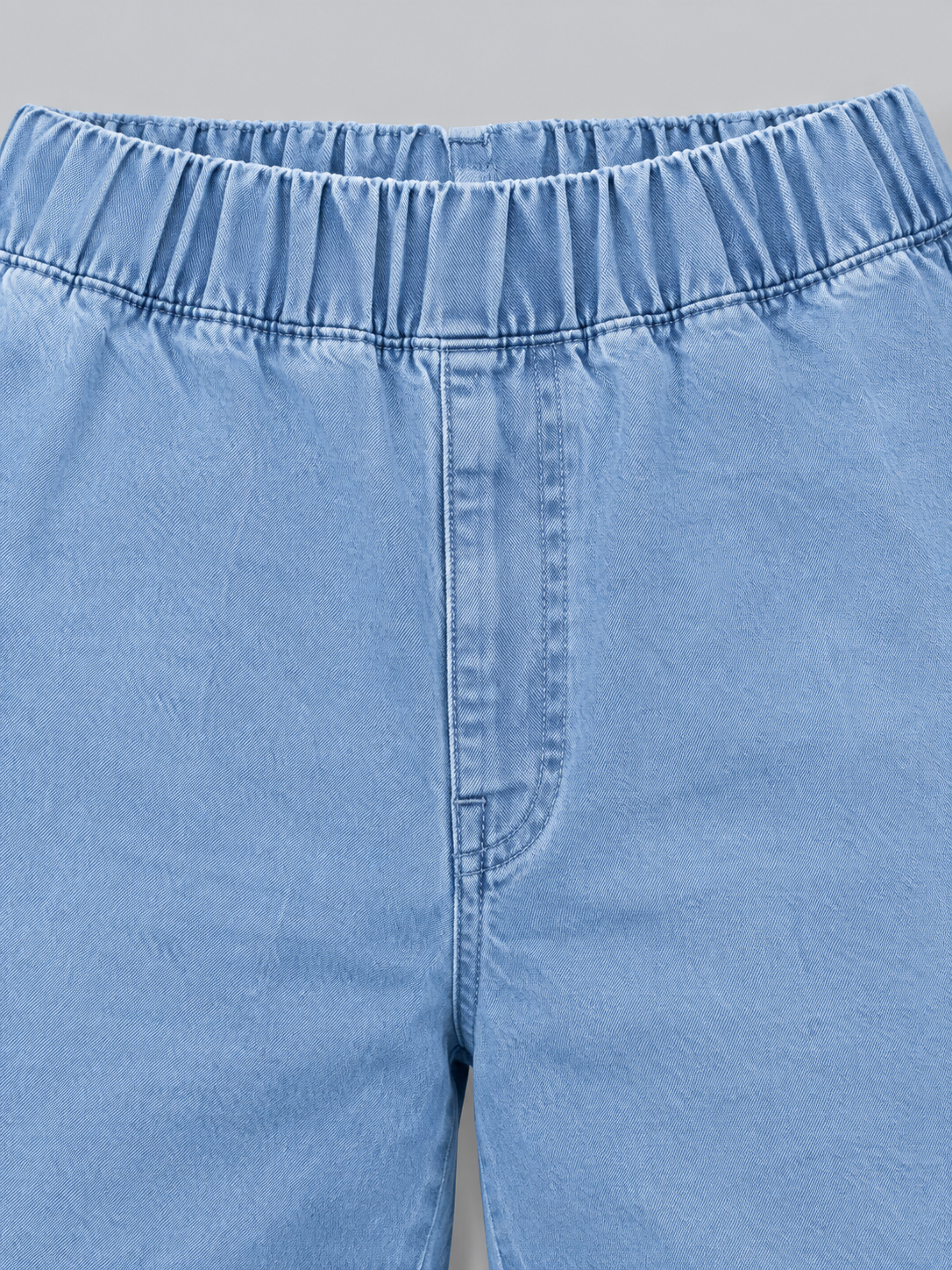 Close-up of the light blue jeans’ gathered elasticated waistband and front pull-on fastening detail.