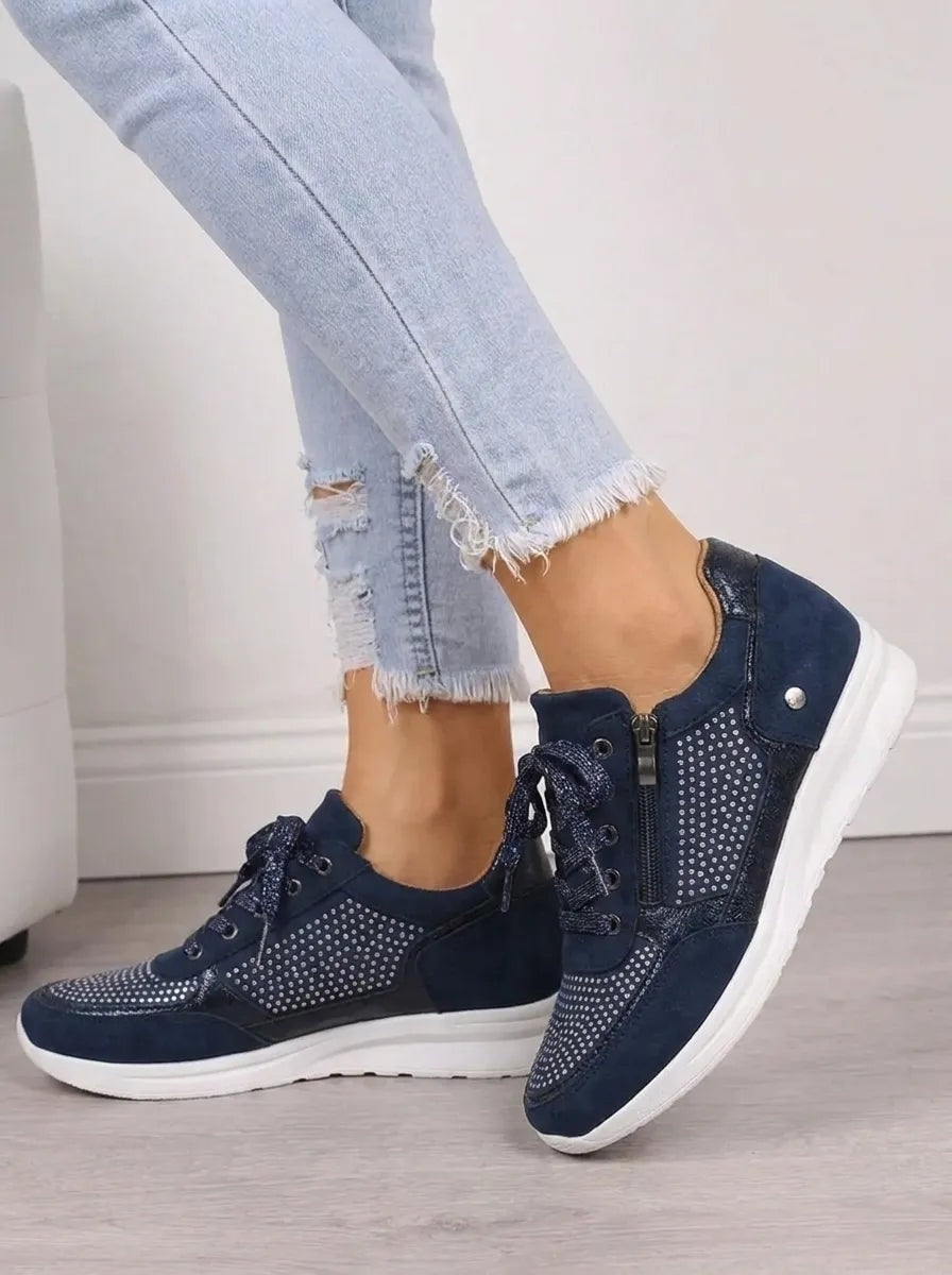 Side view of navy lace-up sneakers showing the outer side zips, sparkling side panels, and raised white soles.