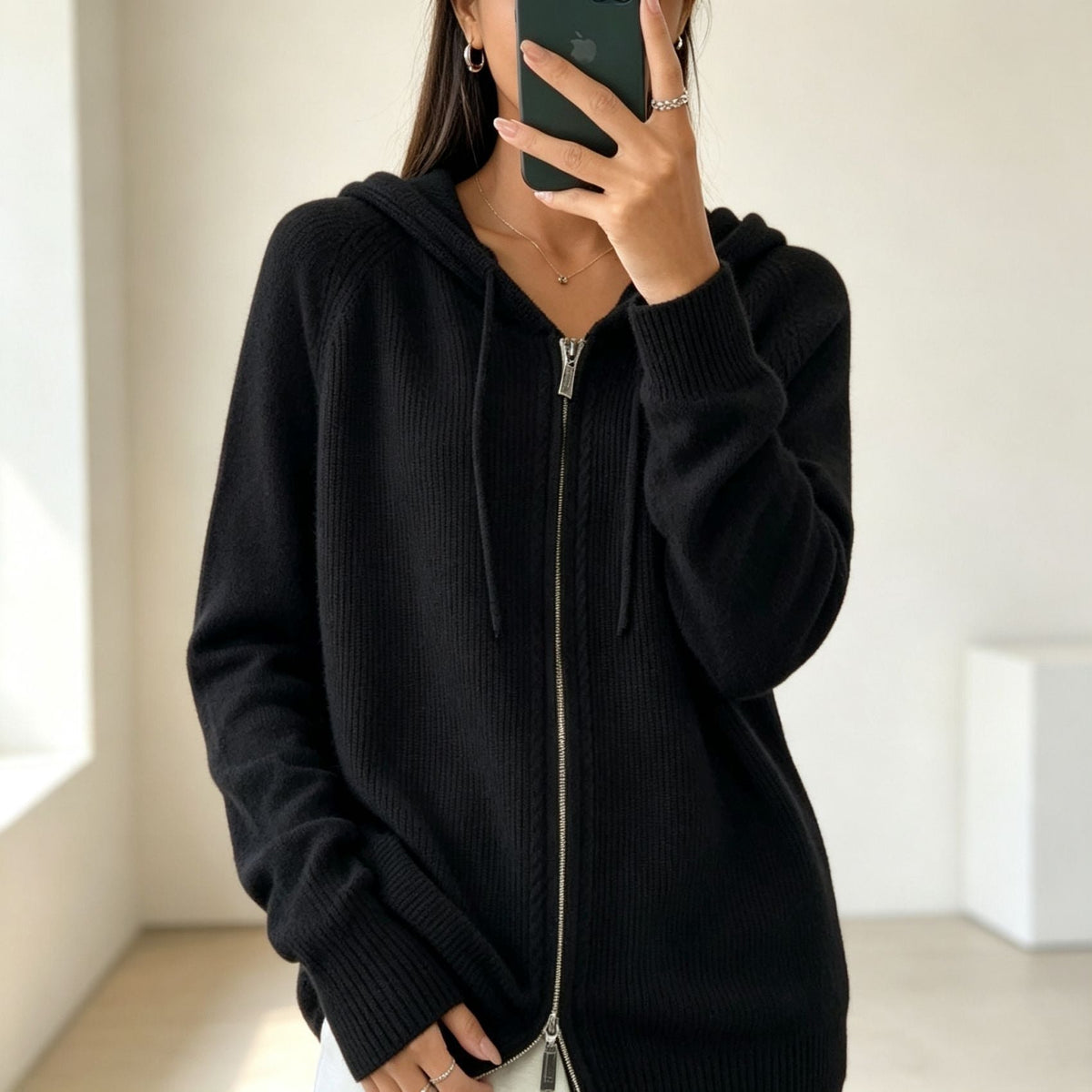 Black hooded cardigan with a fully closed front zipper, long sleeves and ribbed cuffs.